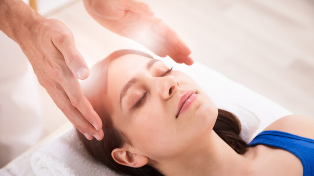 Vrouw ligt op massagestoel met twee handen naast haar hoofd.